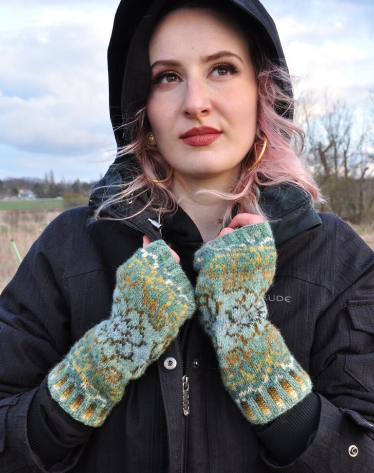 Handgestrickte fingerlose Wollhandschuhe grün Fair-Isle-Muster, getragen auf dunklem Anorak, Wintermode Accessoire